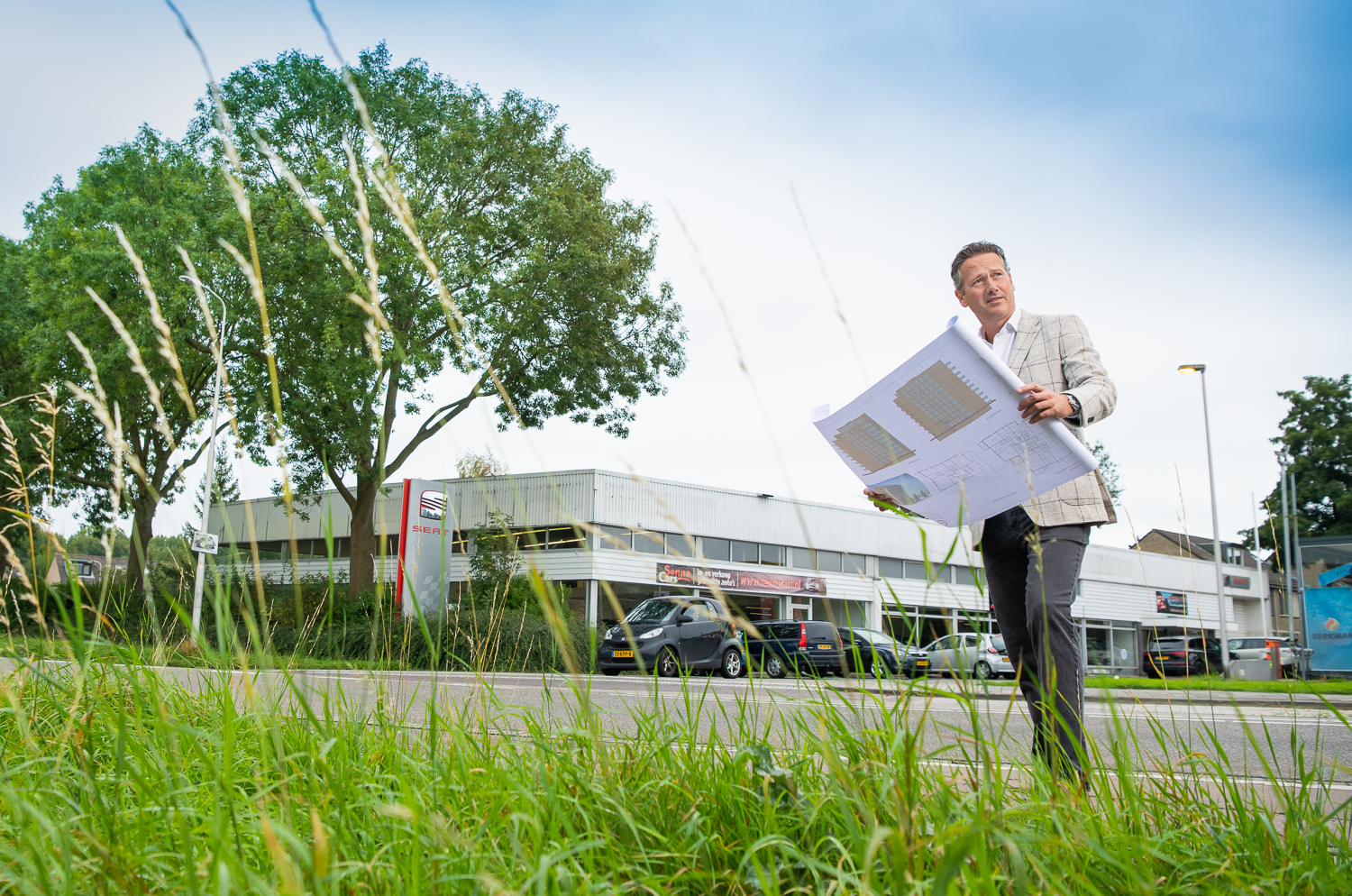 Man met papieren rol in zijn handen voor een pand naast grote bomen in Zoetermeer voor de Transformatiefaciliteit