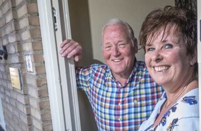 Oude man en vrouw staand in hun deuropening