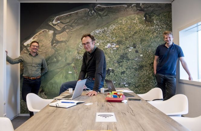 Drie mannen poserend voor de landkaart van Nederland