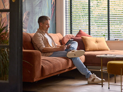 Man zittend op de bank met een tablet in zijn handen
