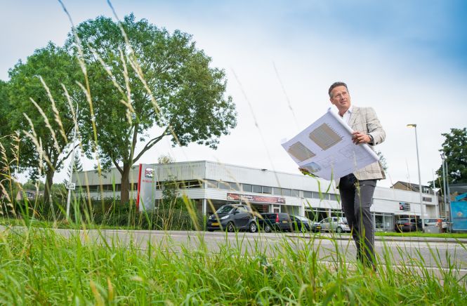 Man met papieren plan in handen kijkend opzij