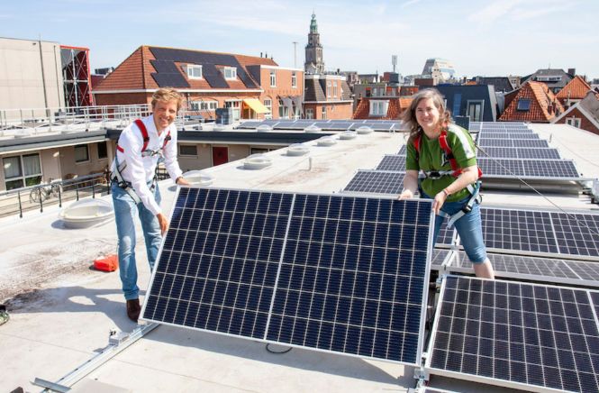 Man en vrouw op een dak staand naast meerdere zonnepanelen