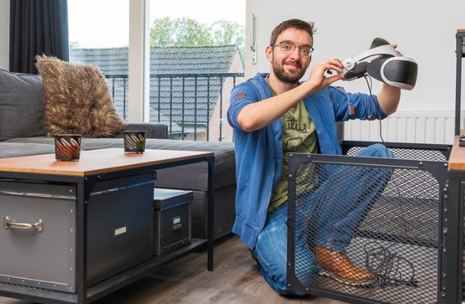 Man hurkend met een vr bril in zijn handen