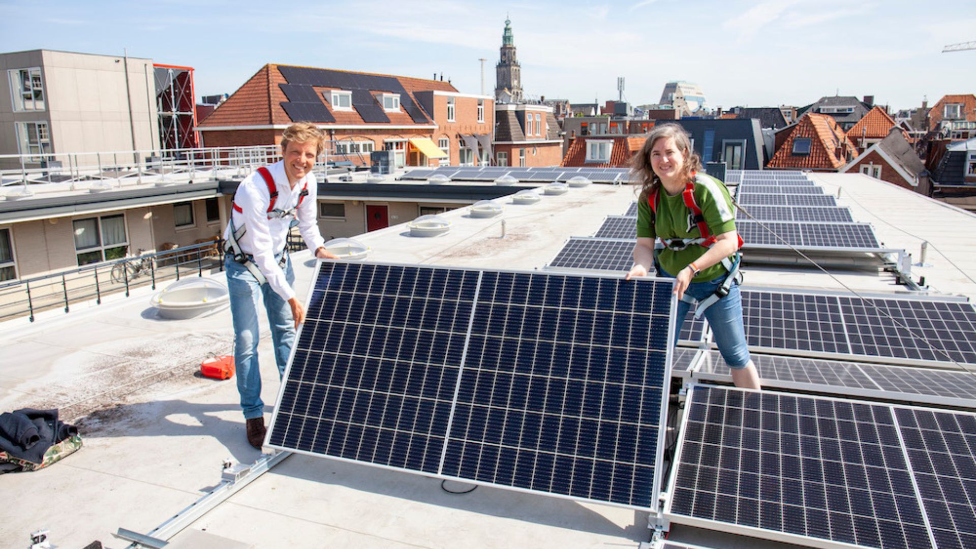 Man en vrouw op een dak staand naast zonnepanelen verkregen dankzij het Realisatiefonds
