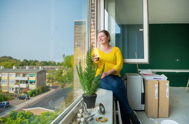 Vrouw die zit in haar raamkozijn terwijl het raam open staat