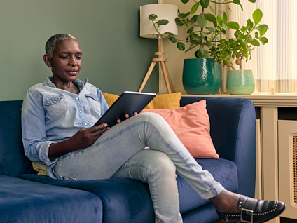 Vrouw zittend op bank met tablet in haar handen