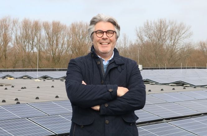 Man met armen gekruist poserend voor een dak vol zonnepanelen