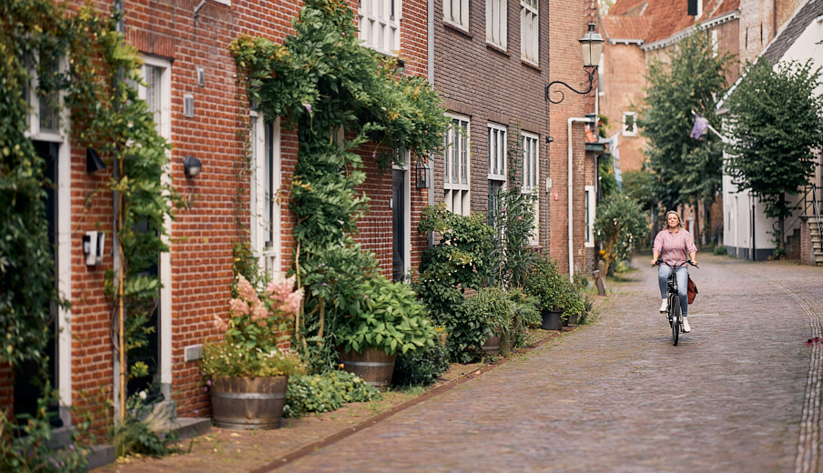 Vrouw die door een woonwijk fietst langs een rij huizen