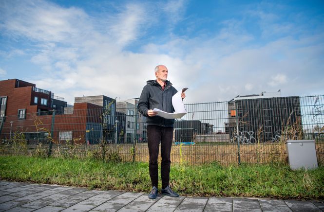 Man met een papieren plan in zijn handen staande op Buiksloterham