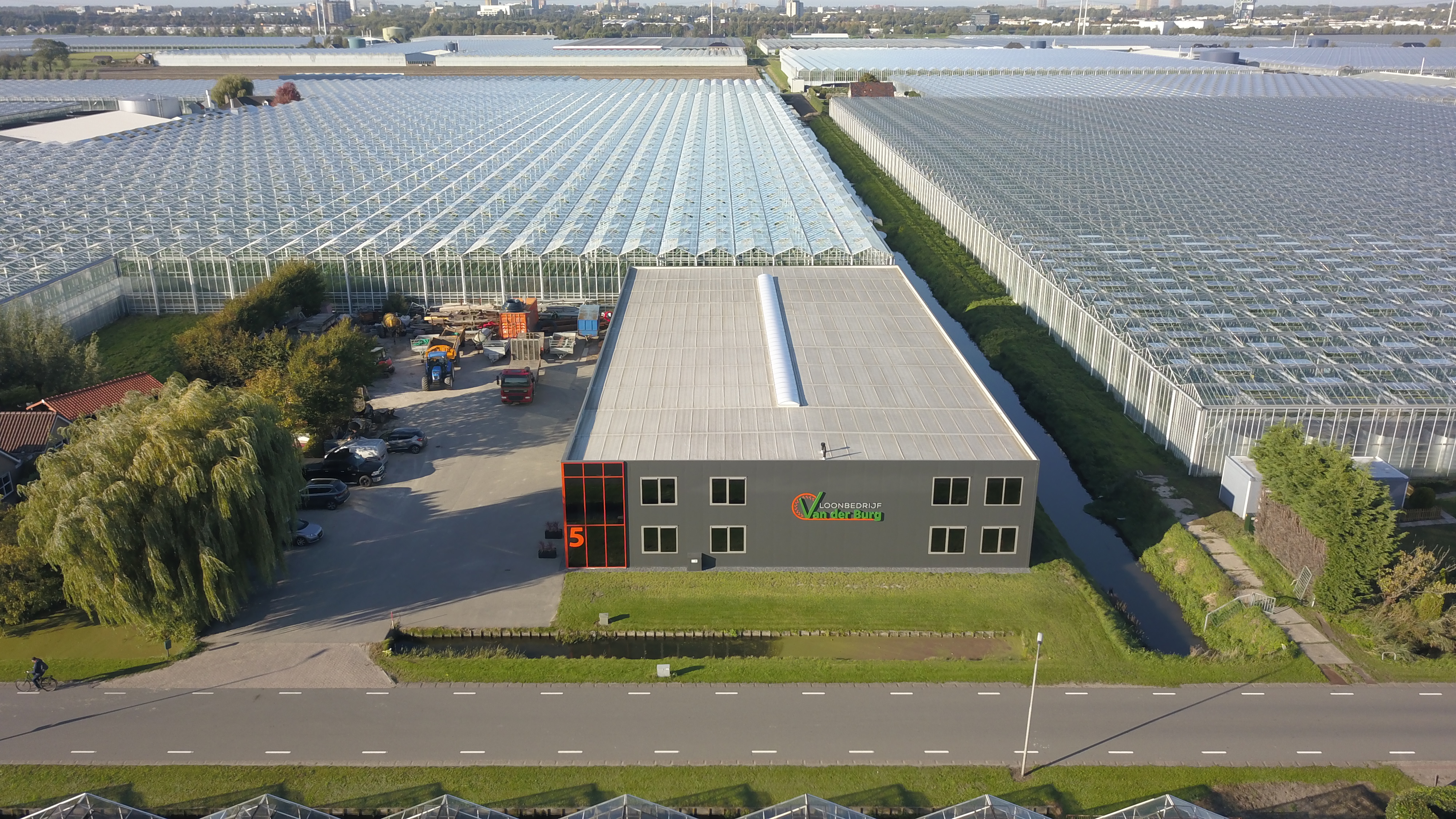 Luchtfoto van meerdere kassen naast een loonbedrijf die verbouwd wordt