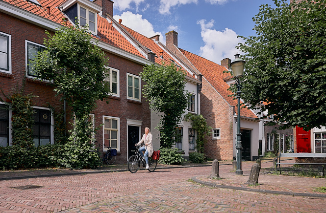 Vrouw op een fiets in een woonwijk met een bocht naast haar