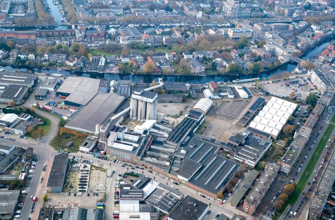 Luchtfoto van een glasfabriek met daaromheen de rest van de stad