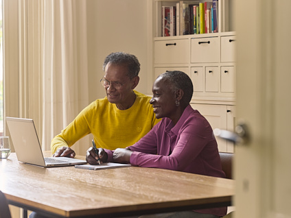 Oudere man en vrouw samen aan een tafel achter een laptop