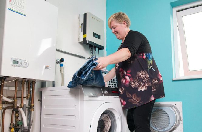 Vrouw die lachend de was doet naast haar cv ketel