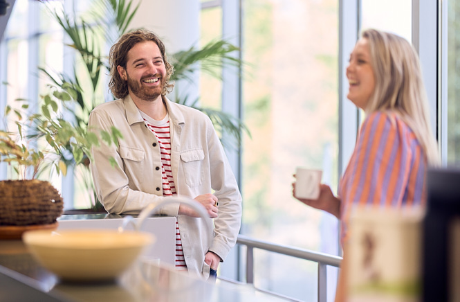Twee collega's van SVn die met elkaar aan het praten zijn met een kopje koffie